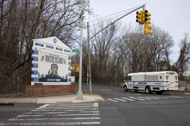 A Department of Corrections bus, used to transport prisoners, drives up to the entrance of the bridge that connects to Rikers Island
